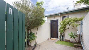 A small house with a paved driveway, a wooden gate, and a door.