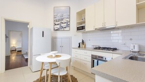 A modern kitchen with white cabinets, a dining table with chairs, and a microwave.