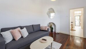A modern living room with a grey sofa, a beige coffee table, and a white wall with a decorative mirror.