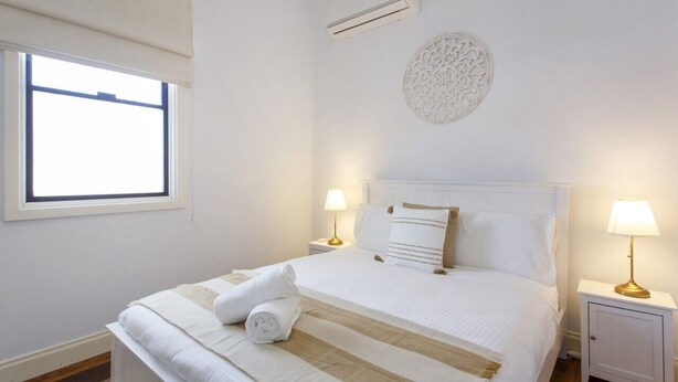 A neatly made bed with a striped bedspread, two bedside lamps, and a decorative wall piece.