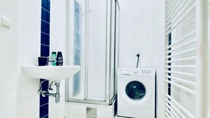 Un bagno compatto con lavandino, cabina doccia e lavatrice.