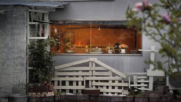 Un espacio exterior rústico con cercado de madera, plantas en macetas y ventana con vista al interior.