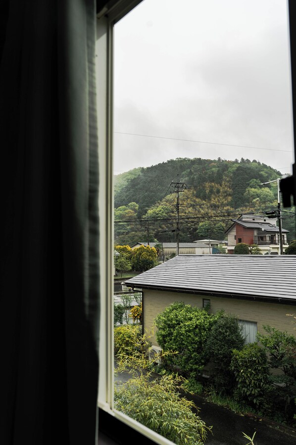 A view from a window overlooking a residential area with houses, a hill with trees, and power lines.