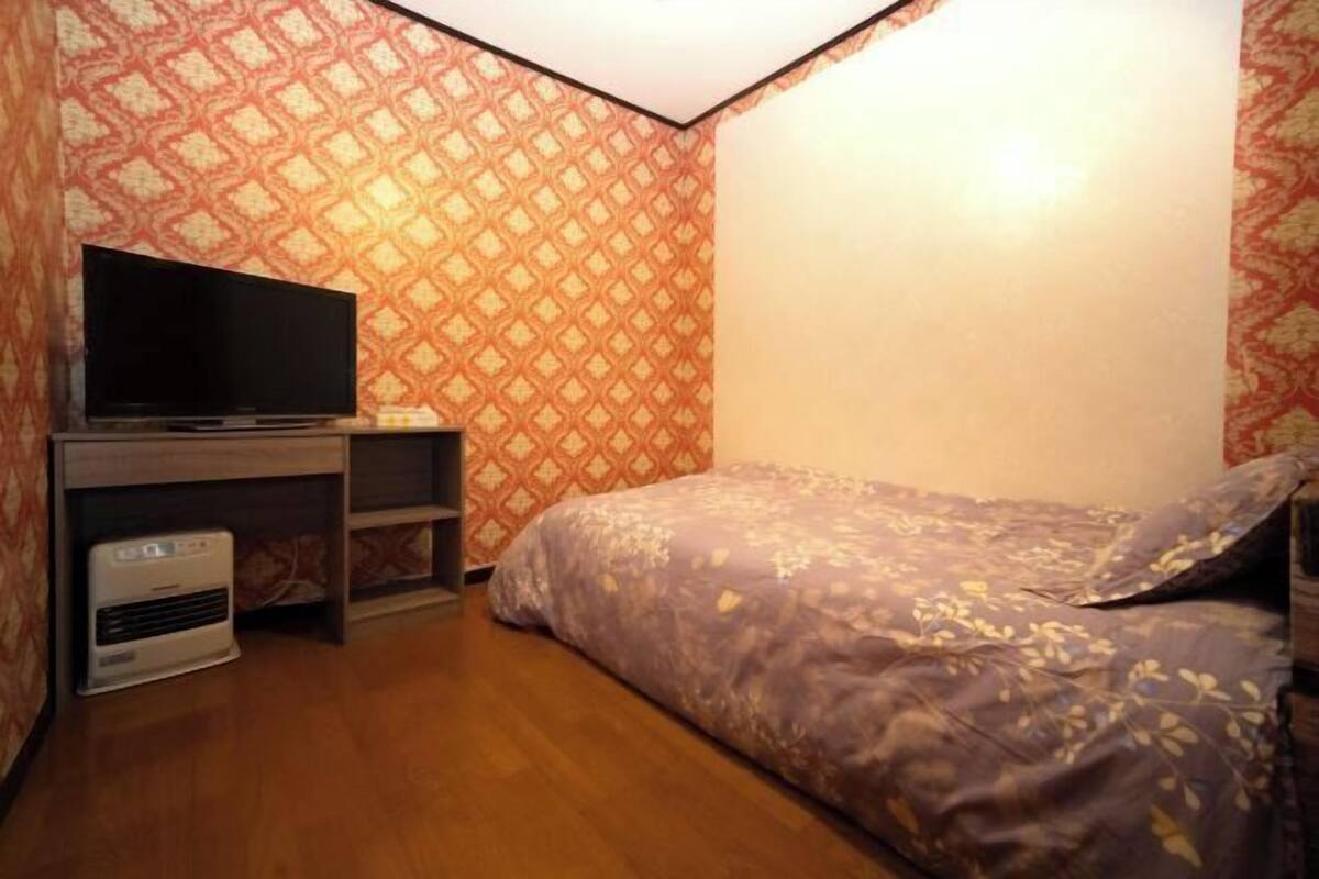 A bedroom with a bed, a TV, and an air conditioner.