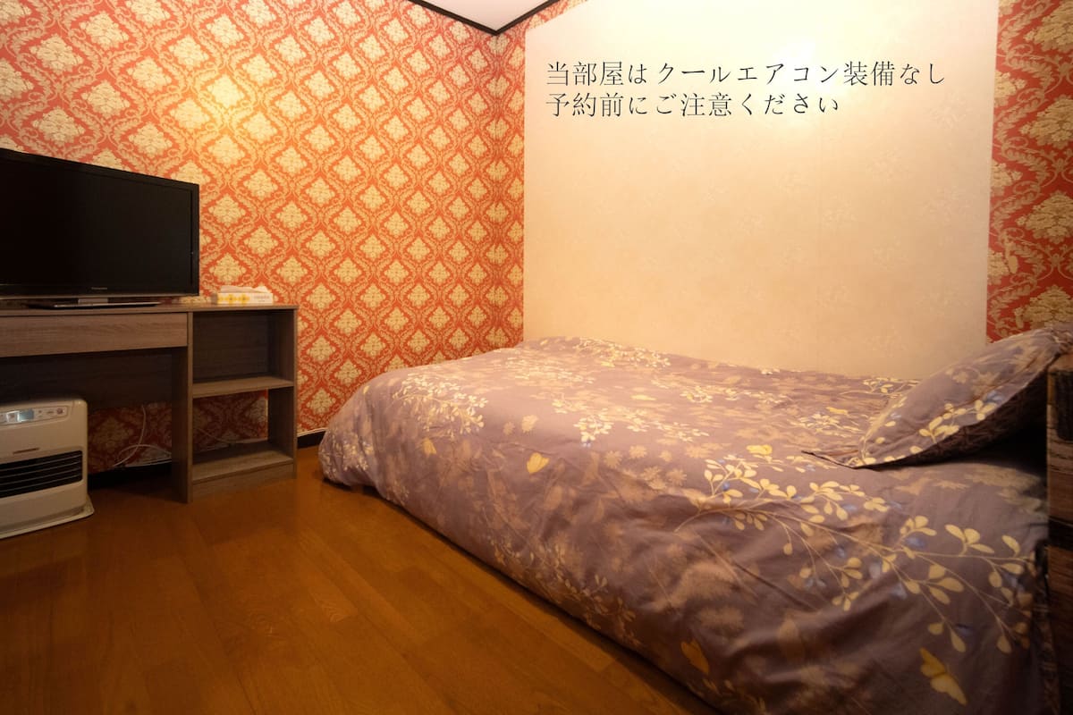 A bedroom with a TV, a heater, and a bed with floral bedding.