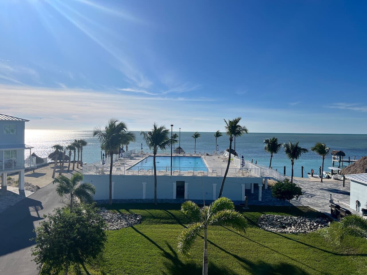 Un complexe hôtelier doté d’une piscine, de palmiers et offrant une vue sur l’océan.