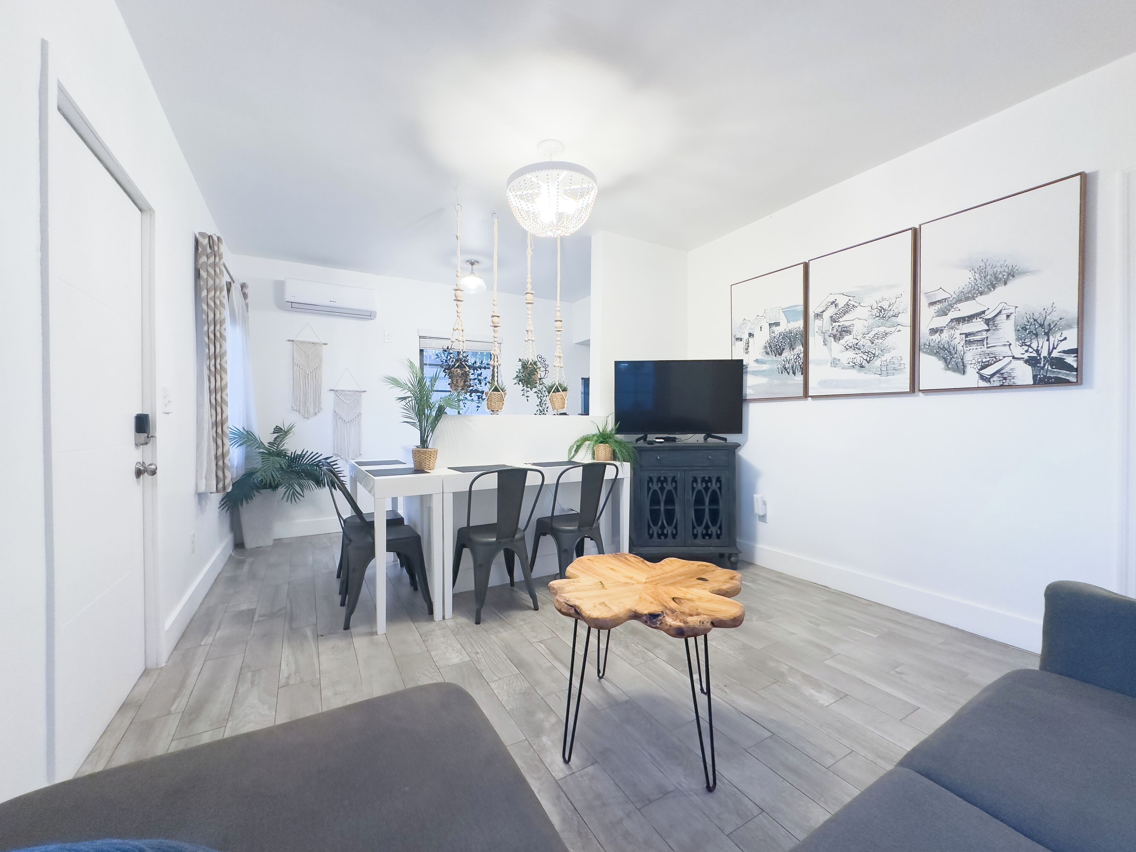 Un salon moderne comprenant un coin repas, un téléviseur et des œuvres d’art accrochées au mur.