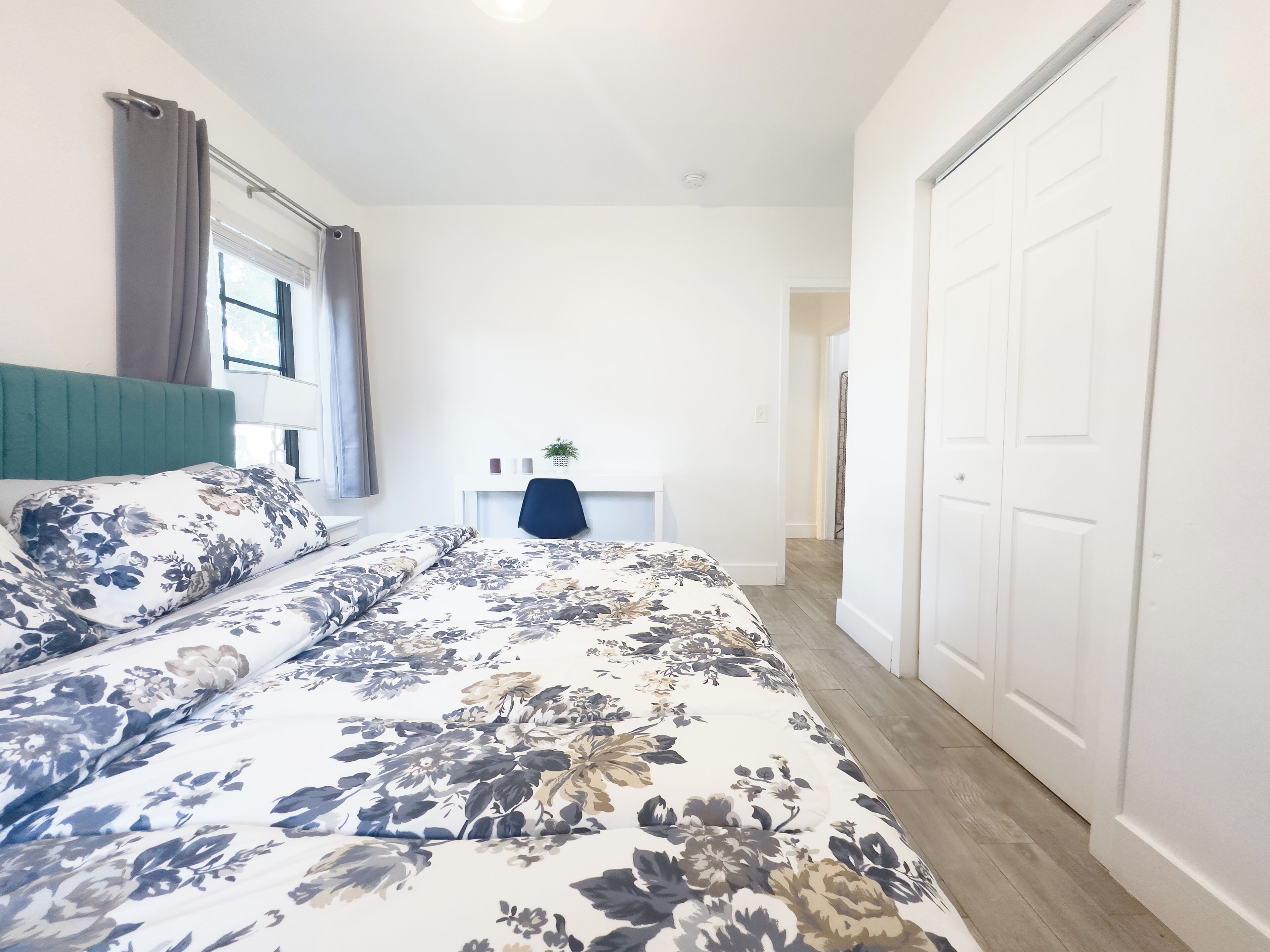 A bedroom with a bed, a desk, and a wardrobe.