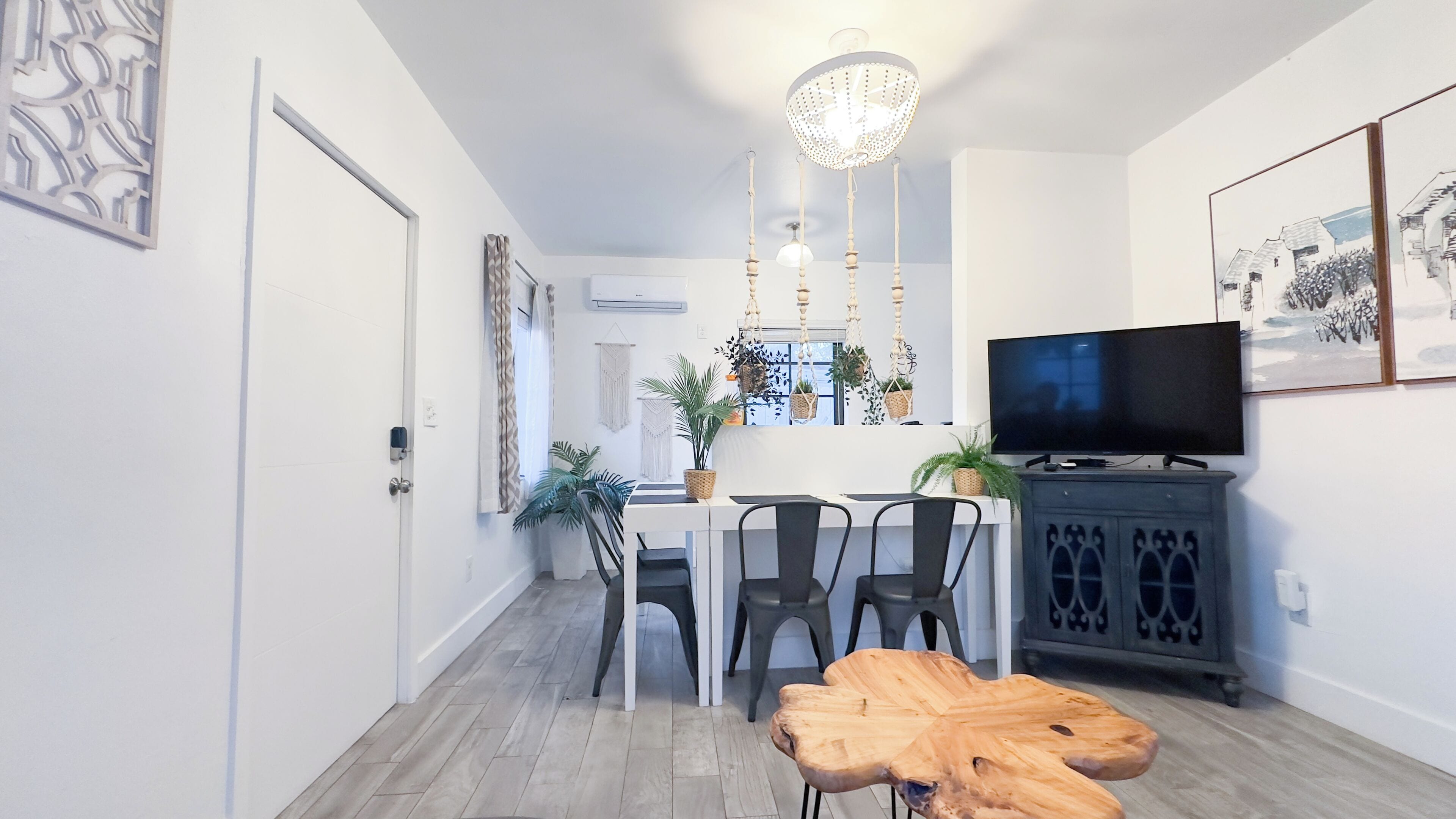 Uma sala de estar moderna com área de jantar, televisão e mesa de centro de madeira.