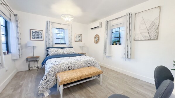 A bedroom with a bed, bedside tables, a bench, and artwork on the walls. - Pera House (Miami)