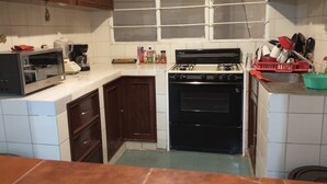 A kitchen with wooden cabinets, a microwave, a stove, and a window above the sink.