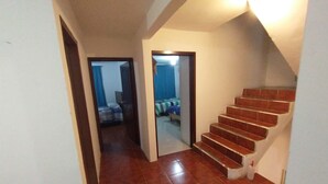 A hallway with a tiled floor leading to a staircase with red tiles.