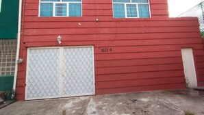 A red building with two windows and a garage door.