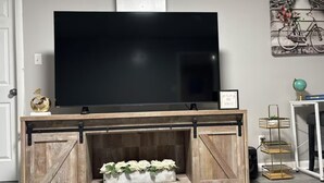 A TV on a wooden entertainment center with a decorative shelf below. - Charming 1-bedroom house in adorable Elizabeth with AC, WiFi (Elizabeth)