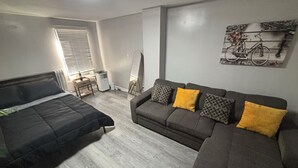 A room with a bed, a sofa, a radiator, a standing heater, and a wall-mounted artwork. - Charming 1-bedroom house in adorable Elizabeth with AC, WiFi (Elizabeth)