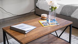 Ein Holztisch mit einem Magazin, einem Buch und einer klaren Vase mit Blumen.