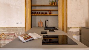 A kitchen with a central island, a built-in shelf with decorative items, and a book on the island.