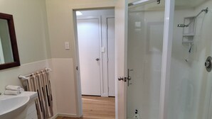 Une salle de bain avec une douche à parois de verre, un lavabo blanc et un porte-serviettes.