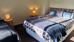 Une chambre à coucher avec un lit, deux tables de chevet et une lampe sur chaque table.