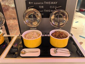 Two yellow pots of food on a counter with a sign indicating directions to the elevator and toilet. - lyf Xian Dayanta by Ascott (Xi'an)