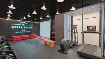 A modern gym with dumbbells, a bench, a treadmill, and a wall with motivational text.