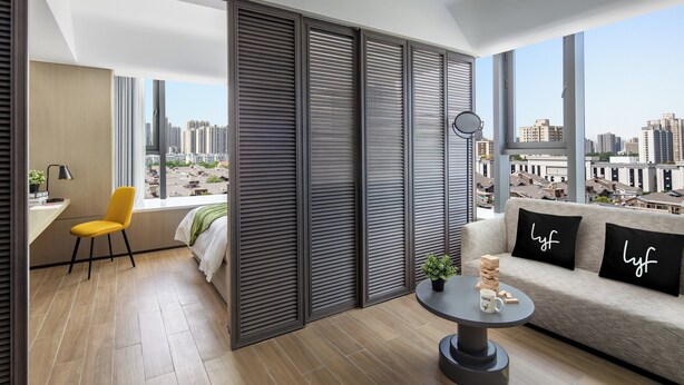 A modern living room with a sofa, a yellow chair, a coffee table, and a view of the cityscape through large windows. - lyf Xian Dayanta by Ascott (Xi'an)
