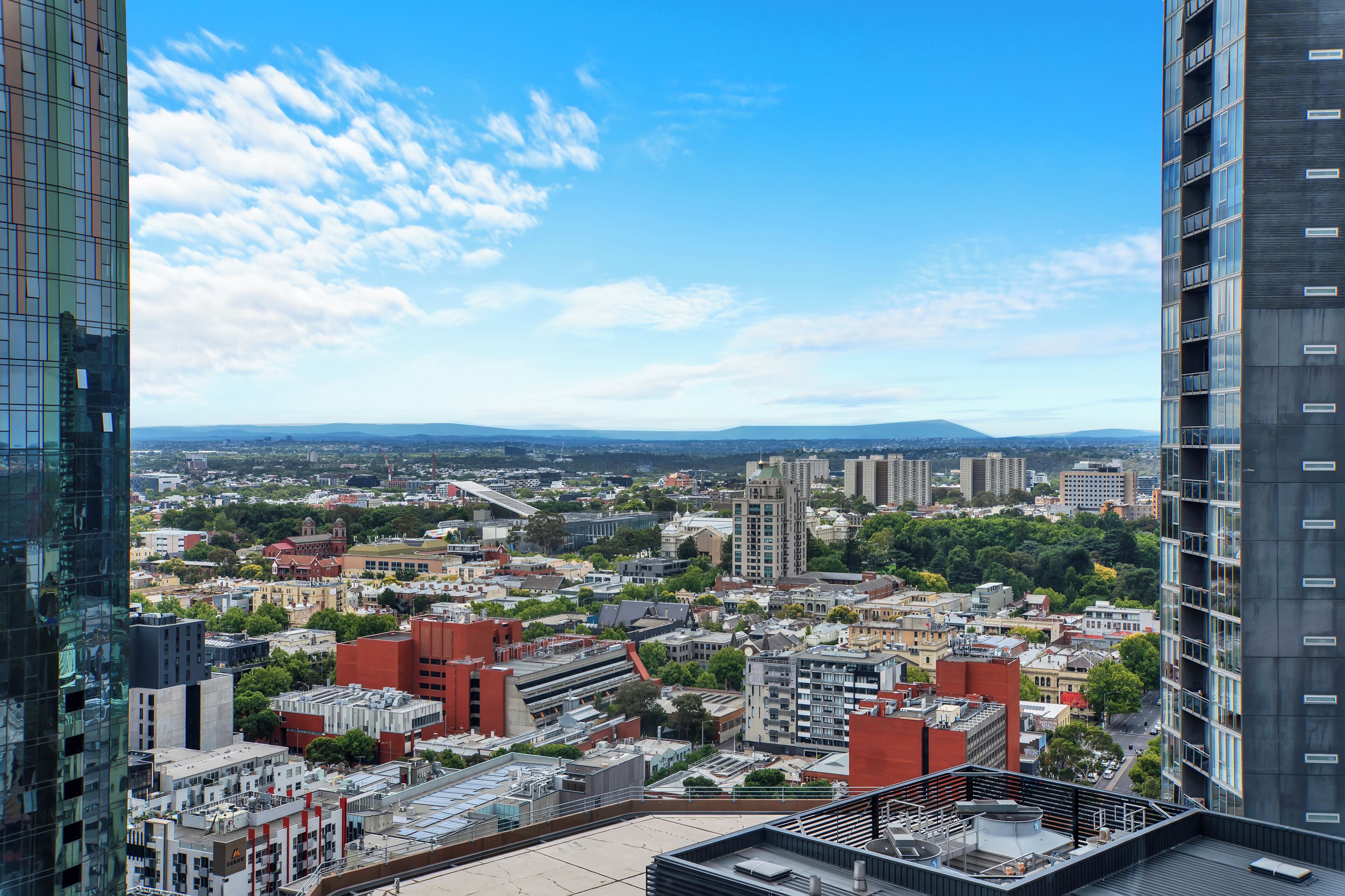 Un edificio alto con vistas a un paisaje urbano, que incluye varios edificios y una cadena montañosa distante.
