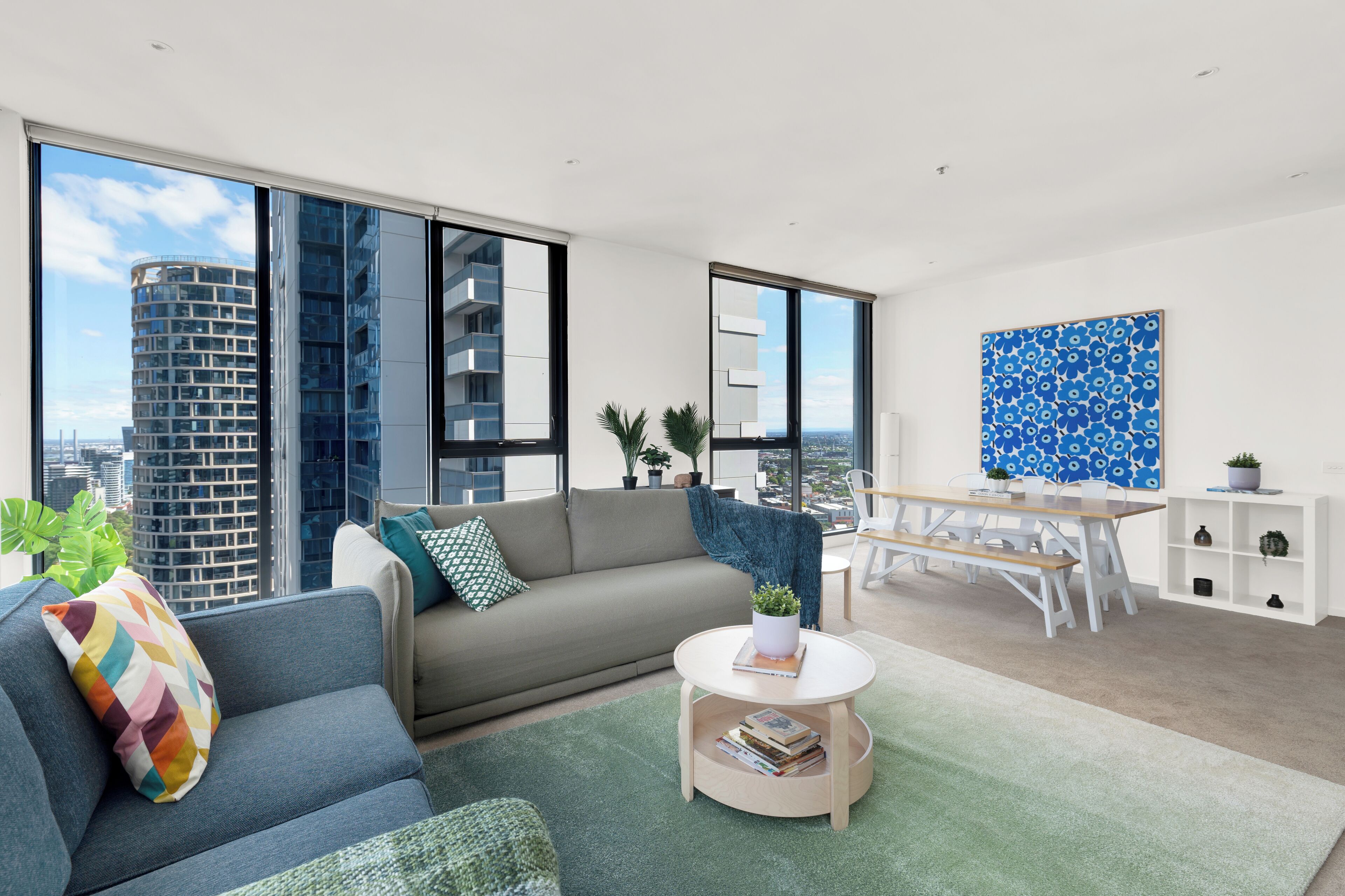 A modern living room with a sofa, a coffee table, and a dining area with a bench.