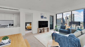A modern apartment with a kitchen, living room, and a large window offering a city view. - Nook Melbourne - Zen Apartments (Melbourne)