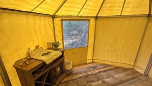 A tent interior with a wooden bench, a small table with items, and a window with a view. -  1-room yurt in Seward (Seward)