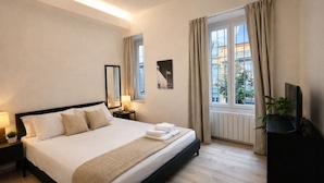 A hotel room with a bed, bedside tables, a TV, a window with curtains, and a view of buildings. - Welcome to the vibrant heart of Moscova, where this exclusive apartment welcomes you with elegance and style, offering you a dream stay in the most dynamic and sophisticated area of Milan. ✨🏙️BEDROOMS: YOUR RELAXING RETREATThe apartment features t (Milan)