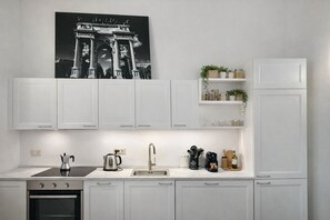 Een moderne keuken met witte kasten, een fornuis, een spoelbak en een koffiezetapparaat.