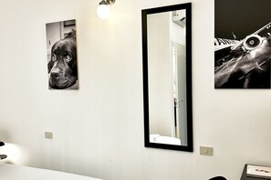Een badkamer met een grote spiegel, een ingelijst foto van een hond en een ingelijst foto van een vliegtuig.