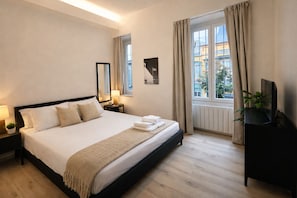 A hotel room with a large bed, a bedside table with a lamp, a TV stand, and a window with curtains. - Welcome to the vibrant heart of Moscova, where this exclusive apartment welcomes you with elegance and style, offering you a dream stay in the most dynamic and sophisticated area of Milan. ✨🏙️BEDROOMS: YOUR RELAXING RETREATThe apartment features t (Milan)