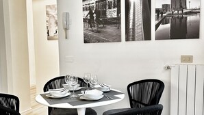 A dining area with a round table set for four, black chairs, and black-and-white photographs on the wall. - Welcome to the vibrant heart of Moscova, where this exclusive apartment welcomes you with elegance and style, offering you a dream stay in the most dynamic and sophisticated area of Milan. ✨🏙️BEDROOMS: YOUR RELAXING RETREATThe apartment features t (Milan)