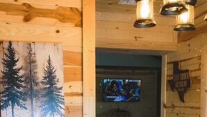 Interior de madera con un cuadro de árboles, piso de piedra y un letrero que dice "The Lodge".