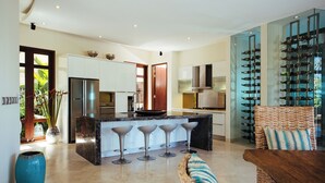 Een moderne keuken met een centraal eiland, barkrukken en een wijnrek.