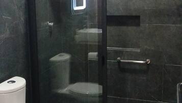 Un baño con ducha acristalada, inodoro y suelo de mármol.