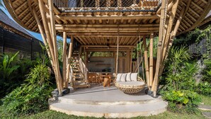 A bamboo structure with a circular seating area, a staircase, and a kitchen area. - Emana Bambooscape (Ubud)