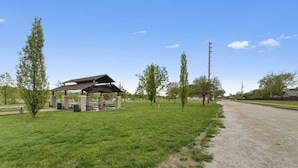 A picnic area with a shelter, picnic tables, and a gravel path. - Steps to Downtown-Boutique Comfort- Bear Suite (Saint Charles)