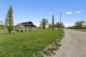 A picnic area with a shelter, picnic tables, and a gravel path. - Steps to Downtown-Boutique Comfort- Bear Suite (Saint Charles)