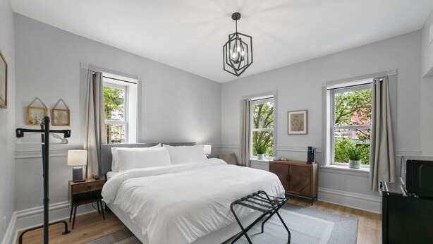 A bedroom with a bed, bedside tables, a lamp, a radiator, and large windows. - Steps to Downtown-Boutique Comfort- Bear Suite (Saint Charles)