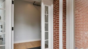 A room with a wooden floor, a black doormat, and a white door with glass panels. - Steps to Downtown-Boutique Comfort- Bear Suite (Saint Charles)