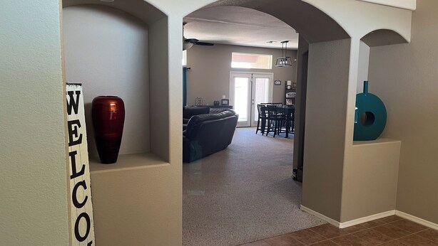 A hallway with a 'WELCOME' sign, a red vase, and a teal circular decoration. - Ridgeline Oasis! (Bullhead City)