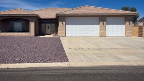 A residential house with a driveway, garage, and a landscaped area with gravel. - Ridgeline Oasis! (Bullhead City)