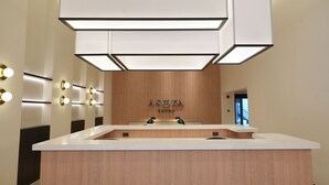 A hotel reception desk with a wooden finish, a modern light fixture above, and a sign reading "ASOKA HOTEL". - Asoka Hotel (Bangkok)