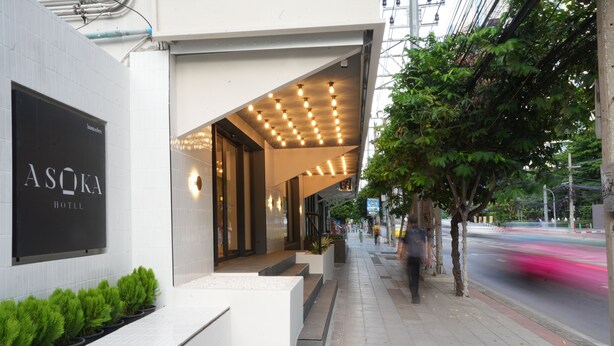 The exterior of Asoka Hotel with a modern design, featuring a clean entrance, a row of potted plants, and a well-lit facade. - Asoka Hotel (Bangkok)