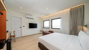 A hotel room with a bed, a desk, a chair, a TV, and a window. - Asoka Hotel (Bangkok)