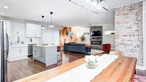 A modern kitchen with white cabinets, a wooden island, and pendant lighting.