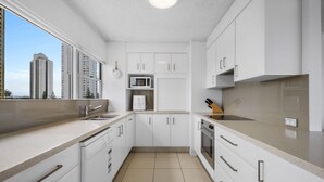 Une cuisine moderne avec des armoires blanches, un four à micro-ondes encastré, un lave-vaisselle et une cuisinière.